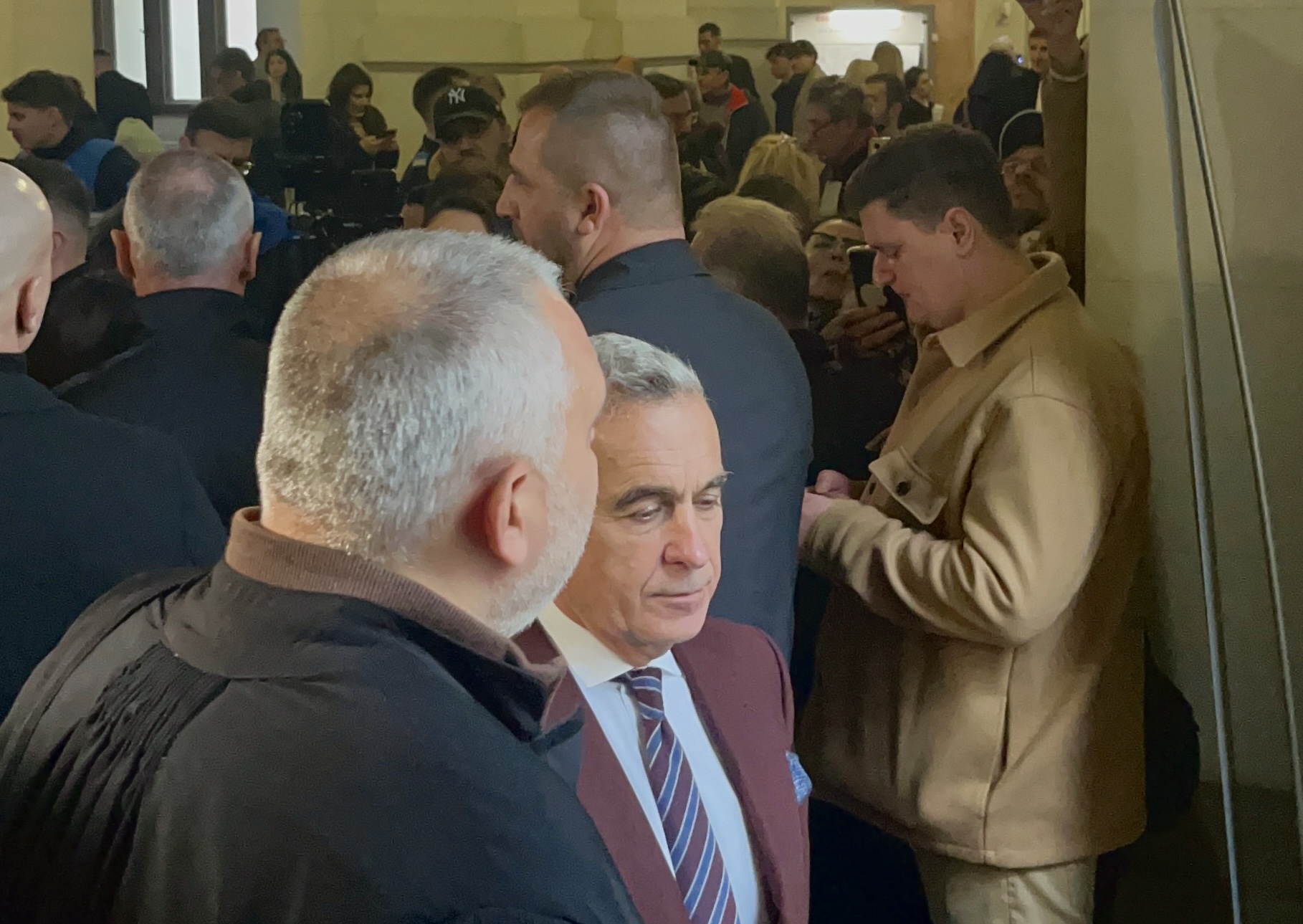 În timpul unei pauze de zece minute, Călin Georgescu iese pe hol pentru a discuta cu avocatul său. Gărzile de corp formează imediat un cerc strâns în jurul lor. Nimeni nu se poate apropia.&nbsp;(sursă foto: Arhiva EVZ)